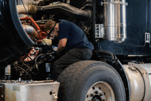a diesel tech sitting on a wheel working on a semi truck