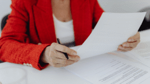 a recruiter wearing a red blazer reviewing a copy of a resume